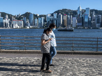 People wearing face masks walk pass the Hong Kong Skyline on July 12, 2022 in Hong Kong, China. The Hong Kong Government announce that it wo...