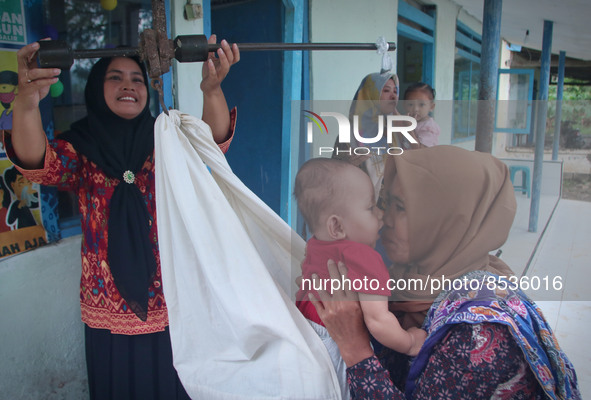 A baby is weighed before receiving a vaccination during a national immunization for children program at an integrated services post in Banyu...