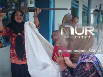 A baby is weighed before receiving a vaccination during a national immunization for children program at an integrated services post in Banyu...