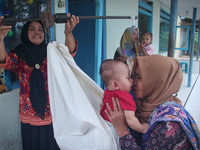 A baby is weighed before receiving a vaccination during a national immunization for children program at an integrated services post in Banyu...