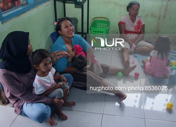 A breastfeeding mother ASI (center) waits for a vaccination queue during the national immunization for children program children at the posy...