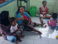 A breastfeeding mother ASI (center) waits for a vaccination queue during the national immunization for children program children at the posy...