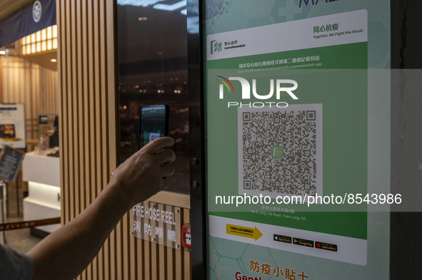 A man scanning the Leave Home Safe QR code with his phone at the entrance of a shopping mall on July 15, 2022 in Hong Kong, China. 