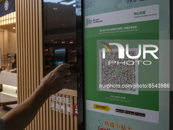 A man scanning the Leave Home Safe QR code with his phone at the entrance of a shopping mall on July 15, 2022 in Hong Kong, China. (