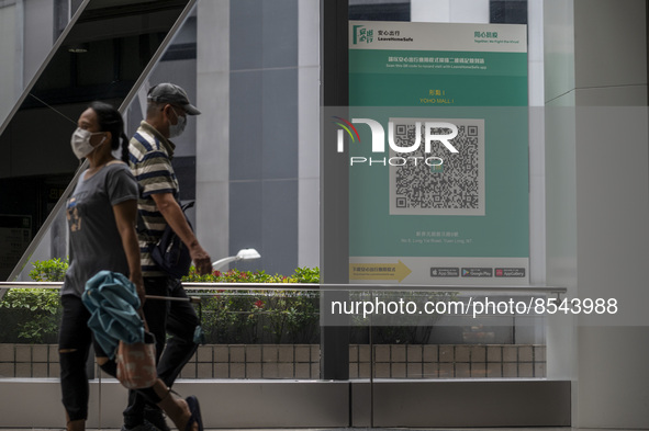 People walk pass a Leave Home Safe QR code placed on a window at the entrance of a shopping mall on July 15, 2022 in Hong Kong, China. 