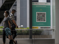 People walk pass a Leave Home Safe QR code placed on a window at the entrance of a shopping mall on July 15, 2022 in Hong Kong, China. (