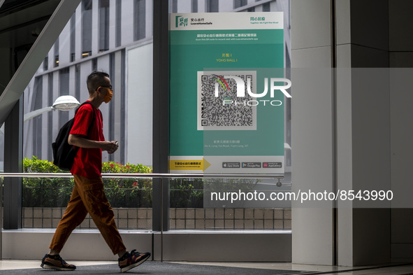 People walk pass a Leave Home Safe QR code placed on a window at the entrance of a shopping mall on July 15, 2022 in Hong Kong, China. 