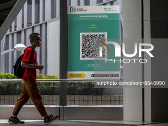 People walk pass a Leave Home Safe QR code placed on a window at the entrance of a shopping mall on July 15, 2022 in Hong Kong, China. (