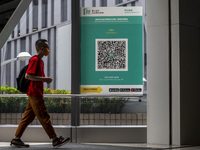 People walk pass a Leave Home Safe QR code placed on a window at the entrance of a shopping mall on July 15, 2022 in Hong Kong, China. (