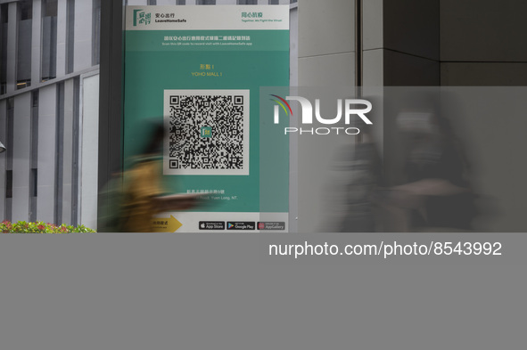 A Long Exposure photo of People walking pass a Leave Home Safe QR code placed on a window at the entrance of a shopping mall on July 15, 202...