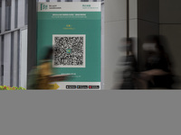 A Long Exposure photo of People walking pass a Leave Home Safe QR code placed on a window at the entrance of a shopping mall on July 15, 202...