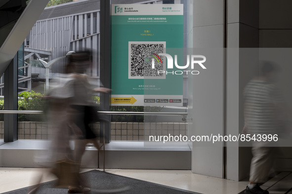 A Long Exposure photo of People walking pass a Leave Home Safe QR code placed on a window at the entrance of a shopping mall on July 15, 202...