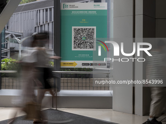 A Long Exposure photo of People walking pass a Leave Home Safe QR code placed on a window at the entrance of a shopping mall on July 15, 202...