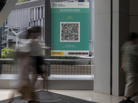 A Long Exposure photo of People walking pass a Leave Home Safe QR code placed on a window at the entrance of a shopping mall on July 15, 202...