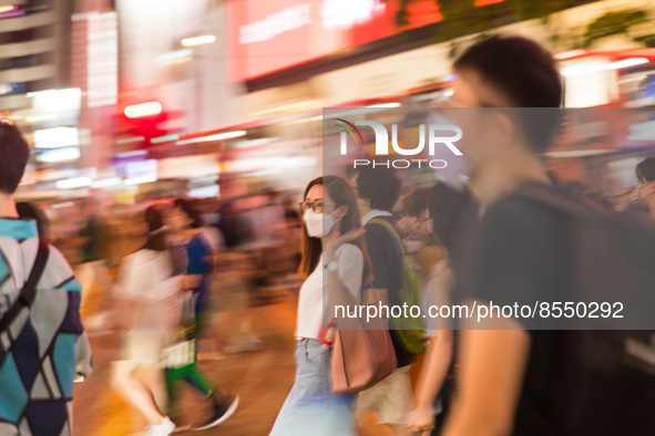 Hong Kong, China, 15 Jul 2022, People cross the street in Causeway Bay in  a panned shot. 