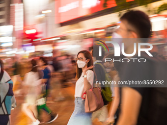 Hong Kong, China, 15 Jul 2022, People cross the street in Causeway Bay in  a panned shot. (