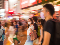 Hong Kong, China, 15 Jul 2022, People cross the street in Causeway Bay in  a panned shot. (