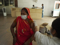 A woman reacts as a health worker inoculates her during a vaccination drive against coronavirus, at a hospital in Noida on the outskirts of...