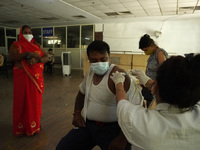 A man reacts as a health worker inoculates him during a vaccination drive against coronavirus, at a hospital in Noida on the outskirts of Ne...