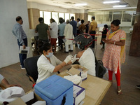 A man wearing a helmet gets inoculated during a vaccination drive against coronavirus, at a hospital in Noida on the outskirts of New Delhi,...