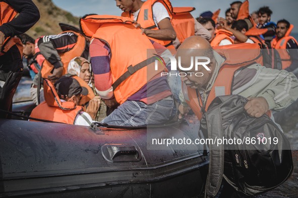 A Syrian man helps pull the dingy he arrived on further into the shores on the island of Lesbos, Greece, on September 26, 2015.  