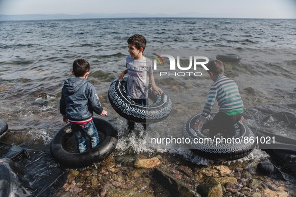 Children play in the waves with rubber rings purchased in case of emergency on the sea, in Lesbos, on September 26, 2015.  