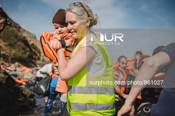 A volunteer carries a child to the shore, in Lesbos, Greece, on September 26, 2015.  