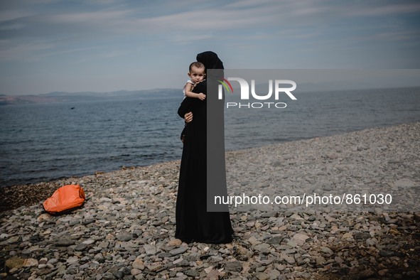 A women holds her child while looking back towards the sea she and her family just crossed from Turkey, in Lesbos, Greece, on September 26,...