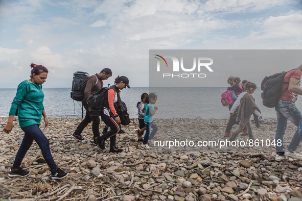 Migrants walk along the beach after they arrive on the Greek island of Lesbos, on September 28, 2015.  