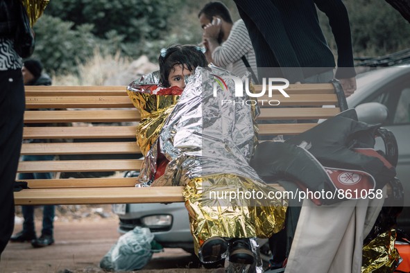 A young girl is first wrapped in a thermal blanket to keep her warm, as she waits to receive dry clothing from the volunteer workers on Lesb...