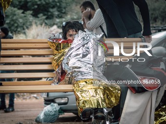 A young girl is first wrapped in a thermal blanket to keep her warm, as she waits to receive dry clothing from the volunteer workers on Lesb...