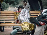 A young girl is first wrapped in a thermal blanket to keep her warm, as she waits to receive dry clothing from the volunteer workers on Lesb...