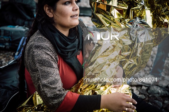 A women wraps her child in a thermal blanket after arriving on the shores of Lesbos, Greece, on September 28, 2015.  