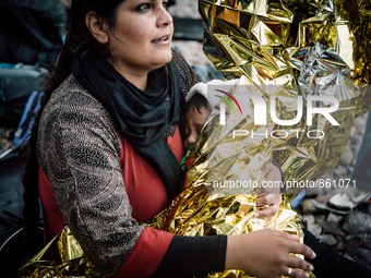 A women wraps her child in a thermal blanket after arriving on the shores of Lesbos, Greece, on September 28, 2015.  (