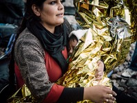 A women wraps her child in a thermal blanket after arriving on the shores of Lesbos, Greece, on September 28, 2015.  (