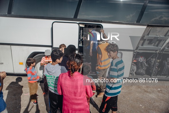 Volunteers help refugees get onto a bus at a temporary transit camp that takes refugees to the top of the island to the port of Mitilini, on...