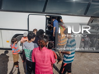 Volunteers help refugees get onto a bus at a temporary transit camp that takes refugees to the top of the island to the port of Mitilini, on...