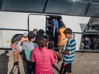 Volunteers help refugees get onto a bus at a temporary transit camp that takes refugees to the top of the island to the port of Mitilini, on...