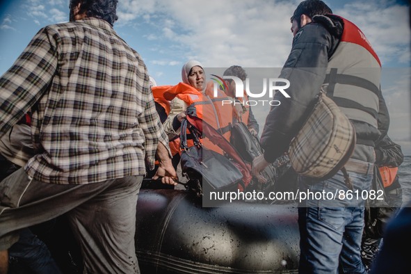 A Syrian woman carries her personal belongings off the dinghy she arrived in, on September 29, 2015.  