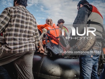 A Syrian woman carries her personal belongings off the dinghy she arrived in, on September 29, 2015.  (