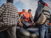 A Syrian woman carries her personal belongings off the dinghy she arrived in, on September 29, 2015.  (