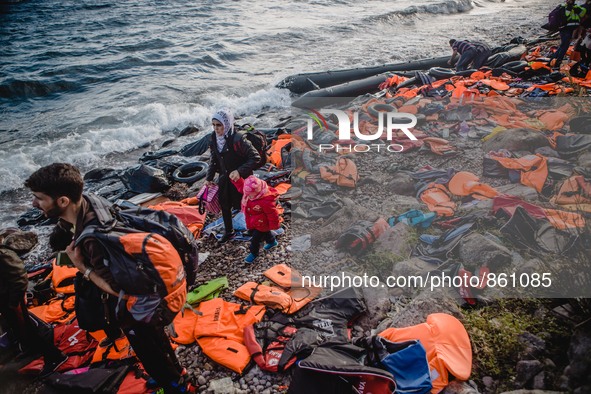 A Syrian women waits for the rest of her family after they have arrived on a stretch of shore covered in lifejackets from other boats on Les...