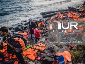 A Syrian women waits for the rest of her family after they have arrived on a stretch of shore covered in lifejackets from other boats on Les...