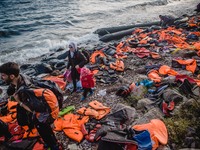 A Syrian women waits for the rest of her family after they have arrived on a stretch of shore covered in lifejackets from other boats on Les...