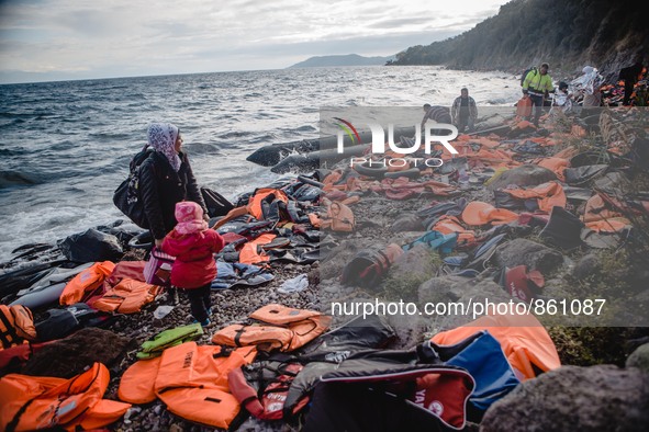 A Syrian women waits for the rest of her family after they have arrived on a stretch of shore covered in lifejackets from other boats on Les...