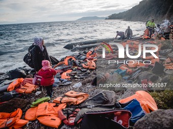 A Syrian women waits for the rest of her family after they have arrived on a stretch of shore covered in lifejackets from other boats on Les...