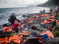 A Syrian women waits for the rest of her family after they have arrived on a stretch of shore covered in lifejackets from other boats on Les...