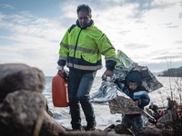 A volunteer helps a child across the rocky shore his boat arrived on in Lesbos, Greece, on September 29, 2015.  (