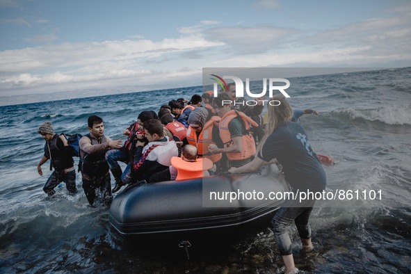 Volunteers help migrants embark from the dinghy they have arrived on, in Lesbos, on September 30, 2015.  