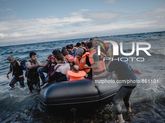 Volunteers help migrants embark from the dinghy they have arrived on, in Lesbos, on September 30, 2015.  (